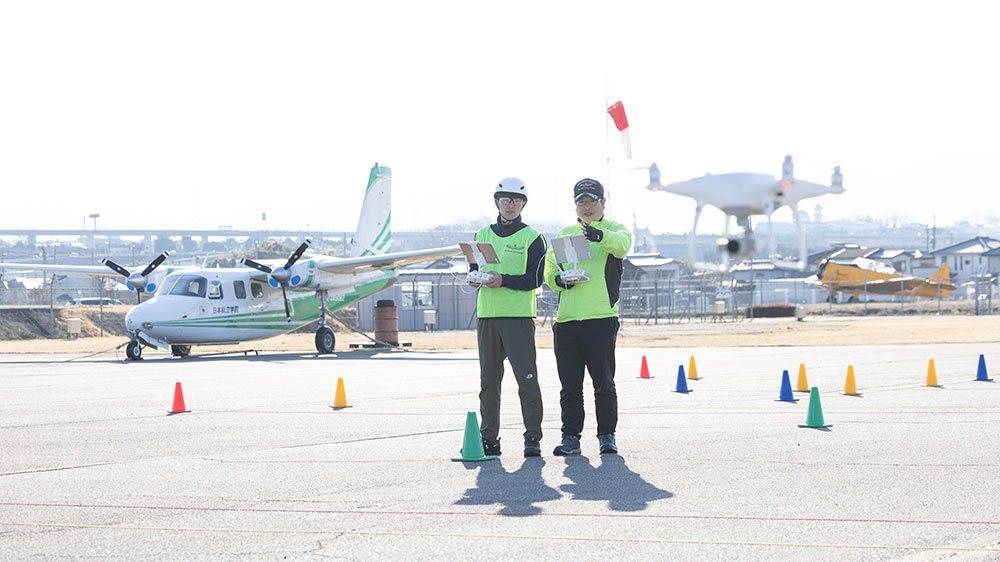滑走路でドローンを操縦する2名の受講生
